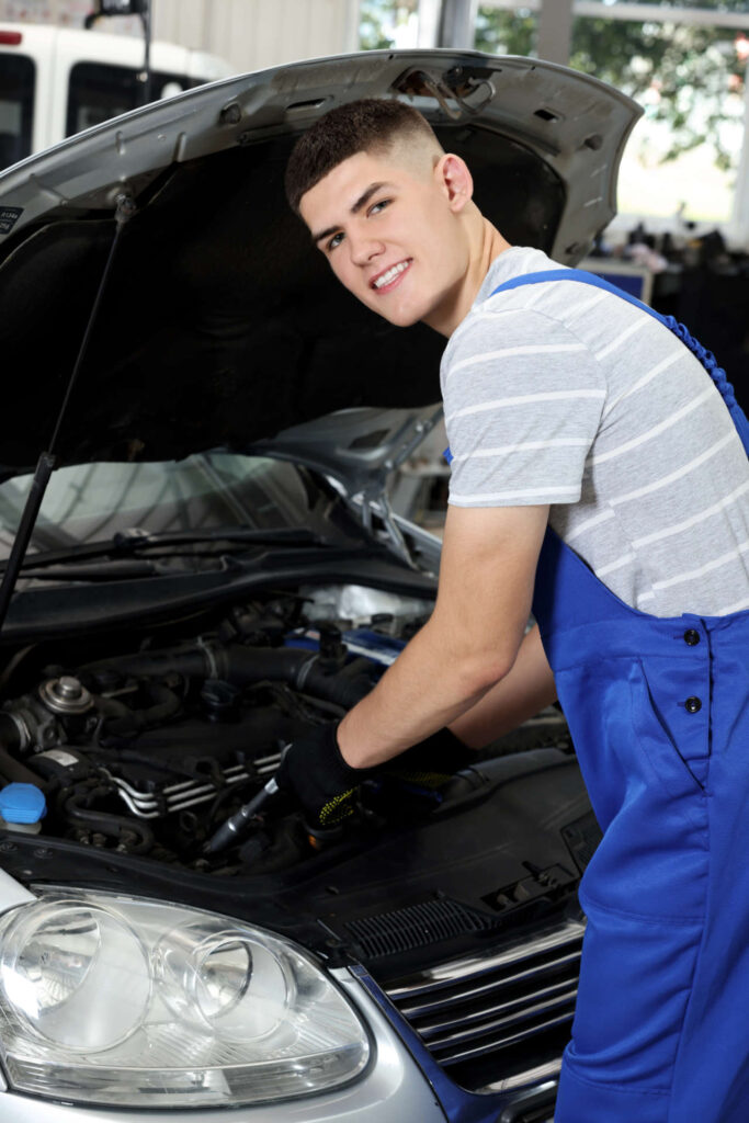 Young auto mechanic fixing car at automobile repair shop